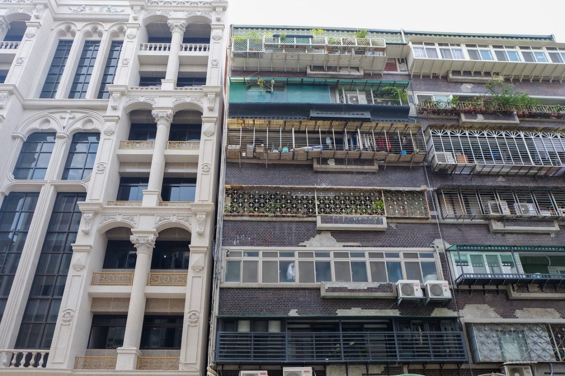 An older building with cages next to a newer one without cages.